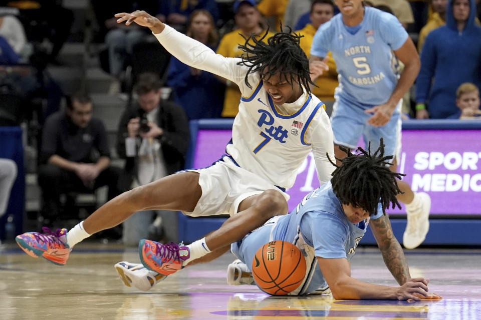 Pittsburgh guard Carlton Carrington (7) lands on top of North Carolina guard Elliot Cadeau (2) as they battle for a loose ball during the first half of an NCAA college basketball game Tuesday, Jan. 2, 2024, in Pittsburgh. (AP Photo/Matt Freed)