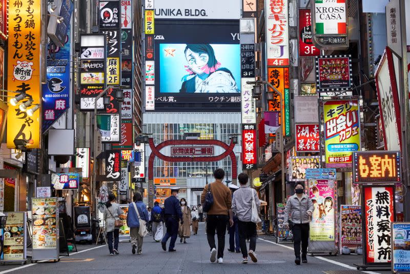 FILE PHOTO: Passersby wearing protective masks stroll through Kabukicho, Tokyo