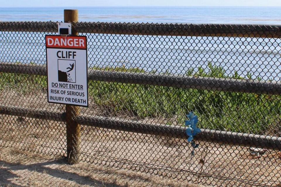 A sign warns people of the cliffs on the other side of fencing along the Isla Vista bluffs.