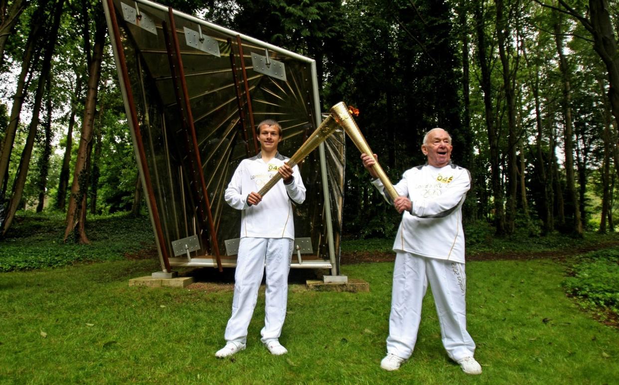 Torchbearer Ryan Hodd Jarvis, left, passes the Olympic flame to Paul Zetter at Cass Sculpture Park in West Sussex during the Olympic torch relay in July 2012 - LOCOG via Getty Images