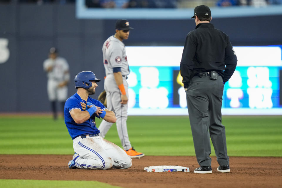 Toronto Blue Jays' Kevin Kiermaier, left, grabs his hand after sliding into second base against the Houston Astros in fifth-inning baseball game action in Toronto, Ontario, Monday, June 5, 2023. (Andrew Lahodynskyj/The Canadian Press via AP)