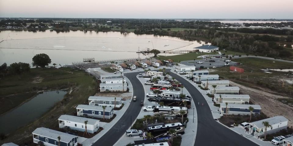 A bird's eye view of Camp Margaritaville RV Resort and Cabana Cabins in Auburndale, Florida at sunset. There are rows of parked RVs and cabins.