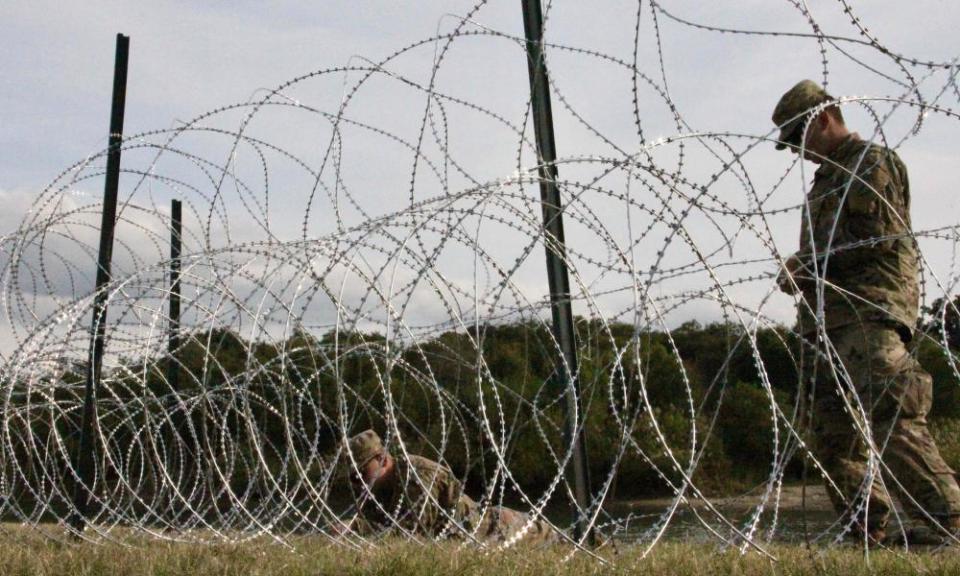 Soldiers work on installing concertina wire at the US-Mexico border.