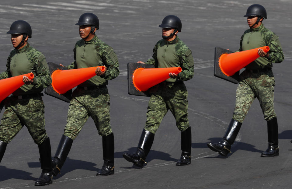 Mexican soldiers carry orange cones to divert traffic from the Zocalo, in preparation for a parade marking the 109th anniversary of the Mexican Revolution, in Mexico City, Wednesday, Nov. 20, 2019. More than a 1,000 participants dressed in time period clothing are expected to act out historical scenes. (AP Photo/Marco Ugarte)