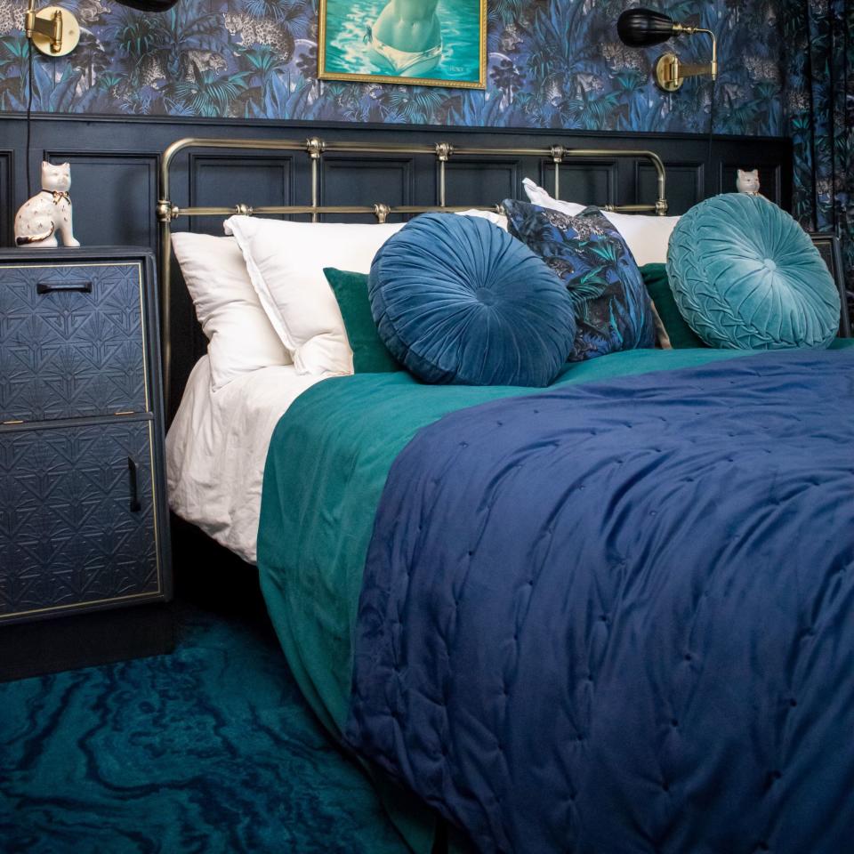 blue bedroom with navy bedding and teal carpet