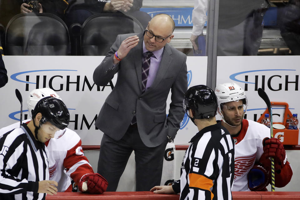 Detroit Red Wings head coach Jeff Blashill, center, talks with referee Mike Hasenfratz (2) during the first period of the team's NHL hockey game against the Pittsburgh Penguins in Pittsburgh, Sunday, Feb. 16, 2020. (AP Photo/Gene J. Puskar)