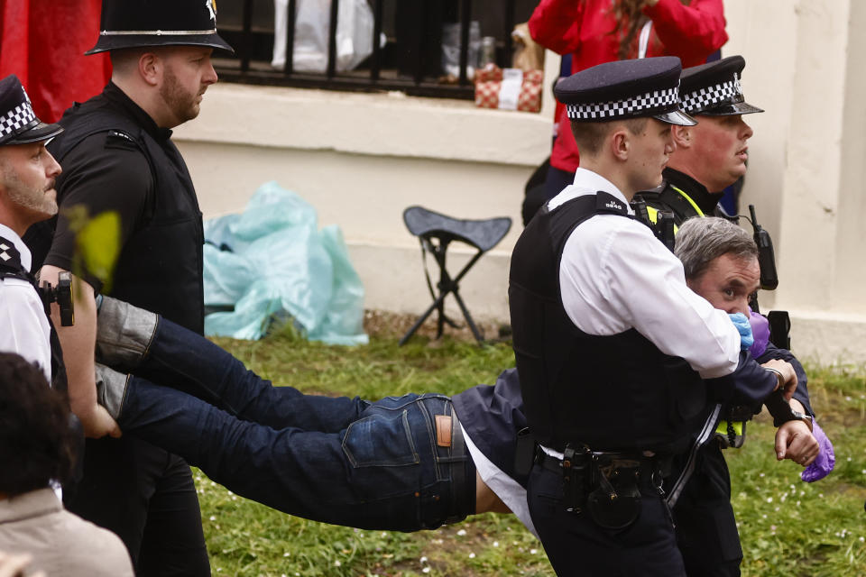 LONDON, ENGLAND - MAY 06: Police officers detain a member of "Just Stop Oil" movement as people gather to watch the procession during the Coronation of King Charles III and Queen Camilla on May 6, 2023 in London, England. The Coronation of Charles III and his wife, Camilla, as King and Queen of the United Kingdom of Great Britain and Northern Ireland, and the other Commonwealth realms takes place at Westminster Abbey today. Charles acceded to the throne on 8 September 2022, upon the death of his mother, Elizabeth II. (Photo by Yara Nardi - WPA Pool/Getty Images)