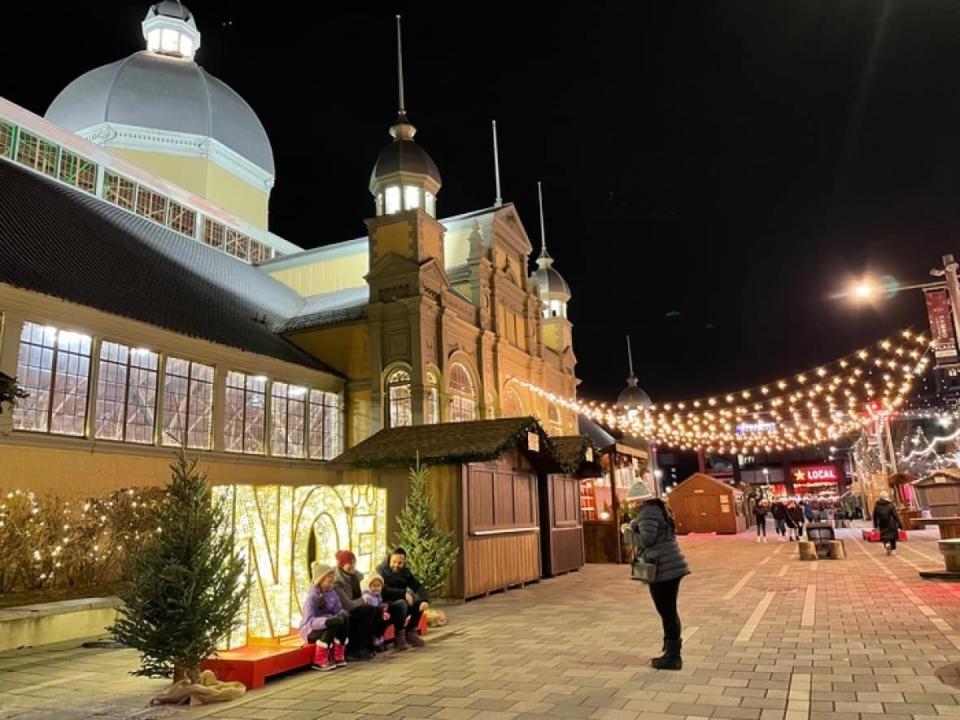 A family takes a photo at the Christmas market at Lansdowne Park on Nov. 29, 2021, during the COVID-19 pandemic.  (Buntola Nou/CBC - image credit)
