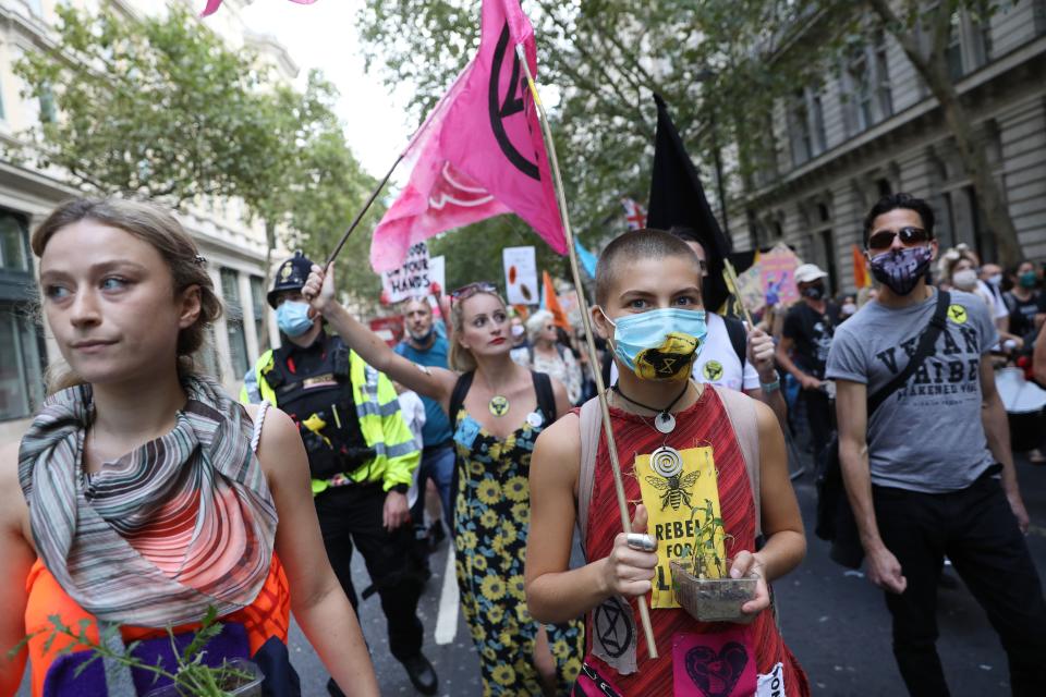 An activist from the climate protest group Extinction Rebellion carries a plant during a march in Trafalgar Square in London on September 1, 2020, at the start of their new season of "mass rebellions". - Climate protest group Extinction Rebellion will target Britain's parliament as part of "mass rebellions" starting from September 1. Other actions will take place around the country. (Photo by ISABEL INFANTES / AFP) (Photo by ISABEL INFANTES/AFP via Getty Images)