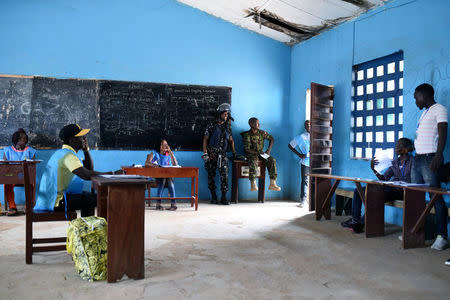 Electoral workers and members of security forces are pictured inside a polling station during a presidential run-off in Freetown, Sierra Leone March 31, 2018. REUTERS/Olivia Acland