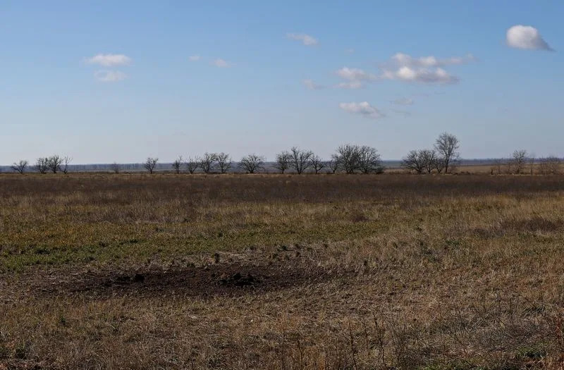 A view of the depression from shelling in field of grain farmer Andrii Povod that has been damaged by shelling and trenches, in Bilozerka