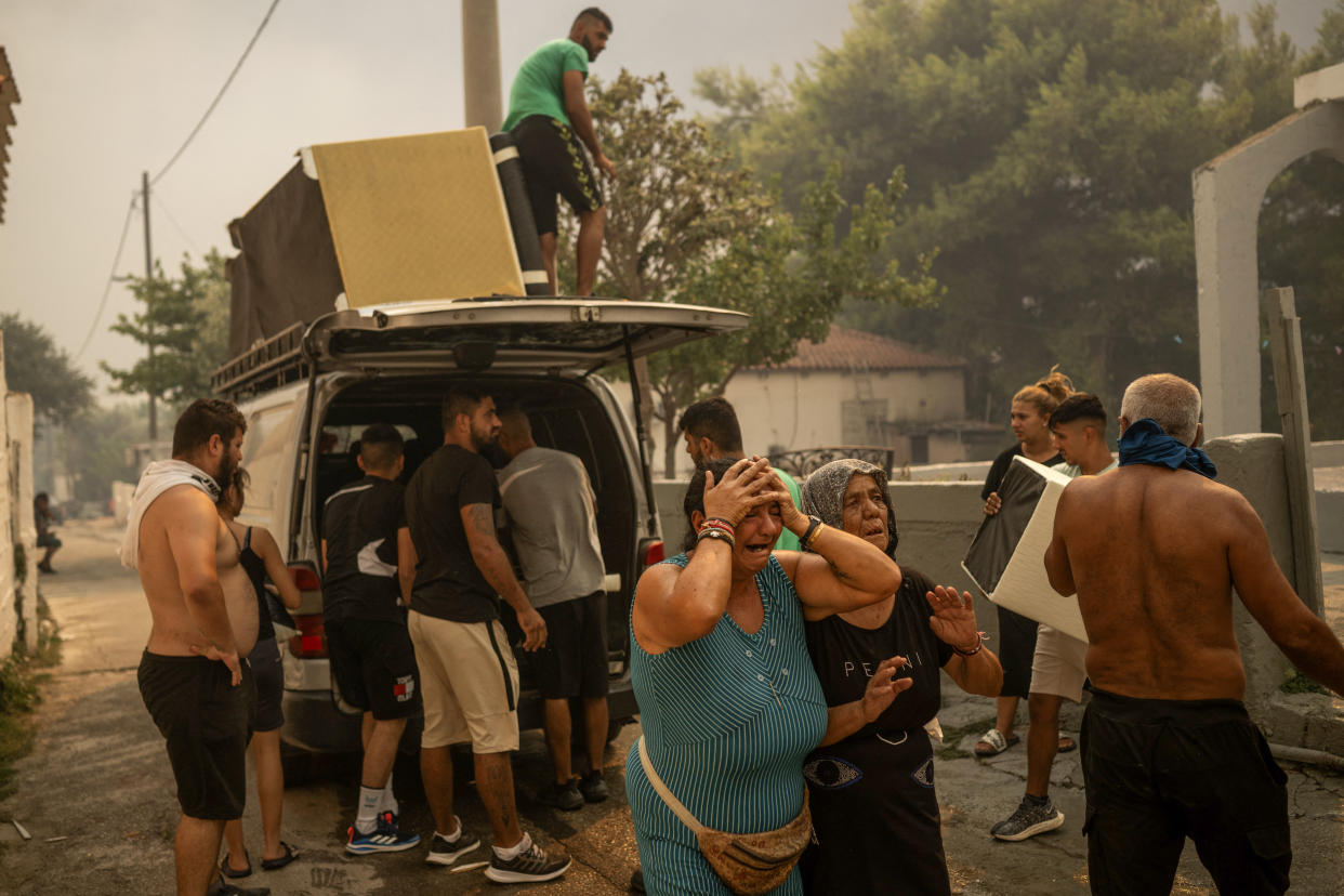 Local residents cry as they try to save some belongings during a wildfire near Penteli, Greece, on Monday.