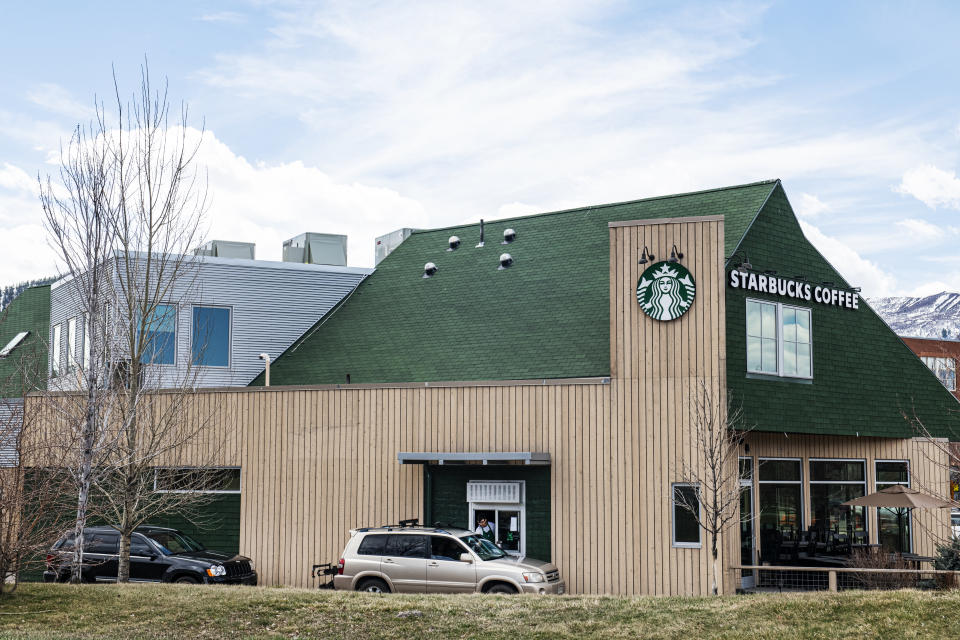 A Starbucks barista hands a drink order out of the drive-thru window in Willits Town Center on Wednesday, April 1, 2020. (Kelsey Brunner/The Aspen Times via AP)