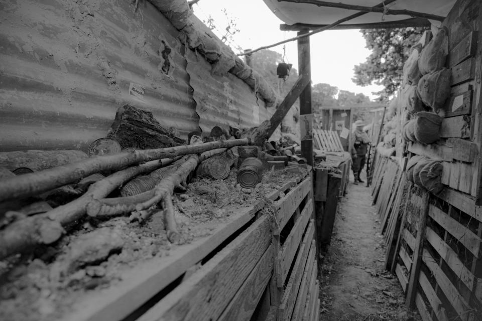 Photograph of a World War I trench with wooden walls and barbed wire, no people present