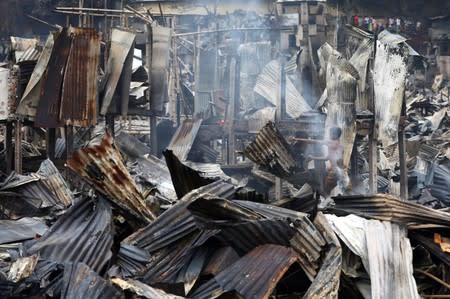 Slum dwellers are seen searching for their belongings from ashes after fire broke out on their shelters in Dhaka