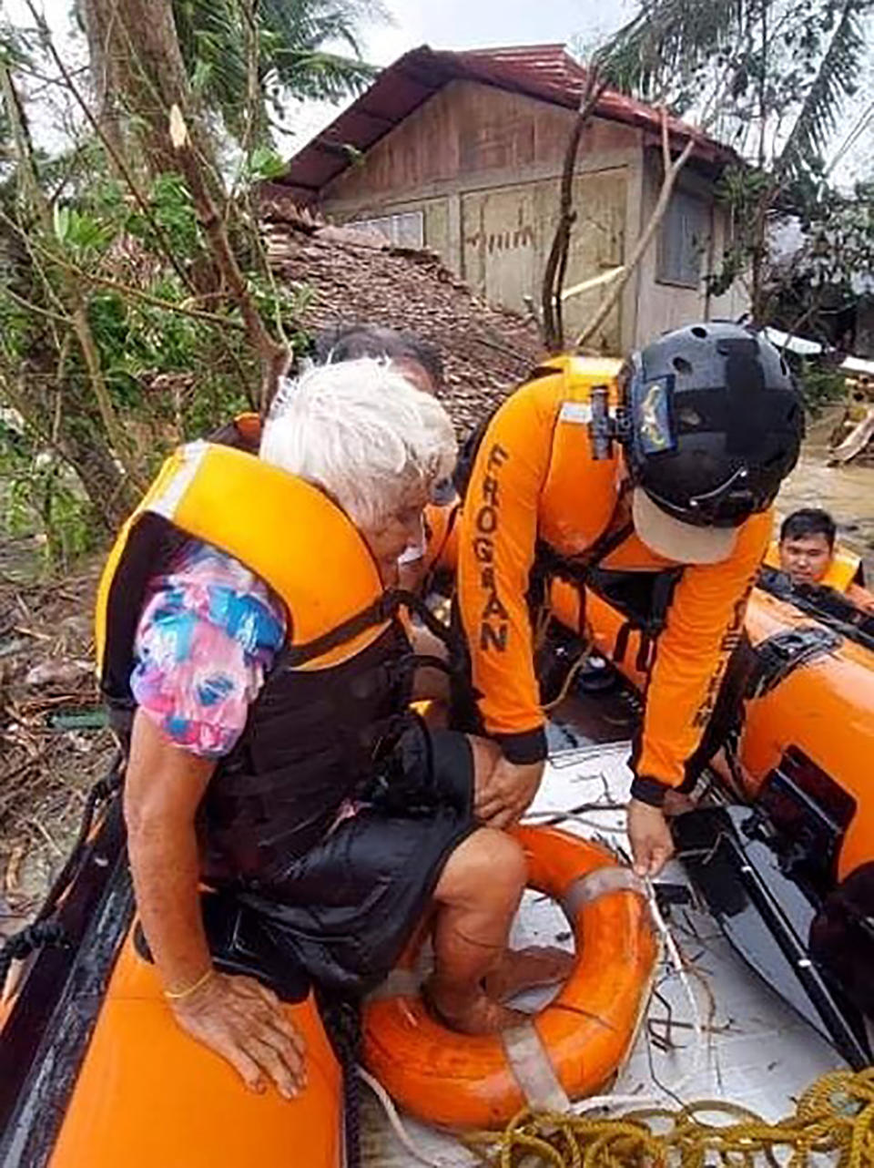 In this photo provided by the Philippine Coast Guard, rescuers assist residents who were trapped in their homes after floodwaters caused by Typhoon Rai inundated their village in Negros Occidental, central Philippines on Friday, Dec. 17, 2021. A strong typhoon engulfed villages in floods that trapped residents on roofs, toppled trees and knocked out power in southern and central island provinces, where more than 300,000 villagers had fled to safety before the onslaught, officials said. (Philippine Coast Guard via AP)