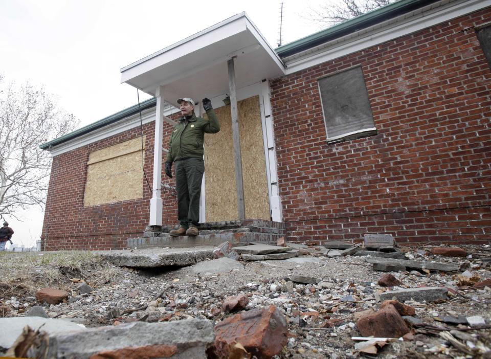 FILE- In this Nov. 30, 2012 file photo, David Luchsinger, superintendent of Statue of Liberty National Monument, and last resident of Liberty Island, poses for a photo at the back door of his Superstorm Sandy-damaged home, on Liberty Island in New York. After hundreds of National Park Service workers from as far away as California and Alaska spent weeks cleaning and making repairs, the island reopen to the public on Independence Day, July 4, 2013. (AP Photo/Richard Drew, File)