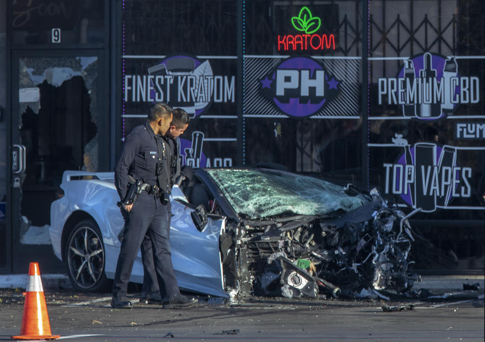 Members of the Los Angeles Police Department examine the remains of a car destroyed in a traffic collision