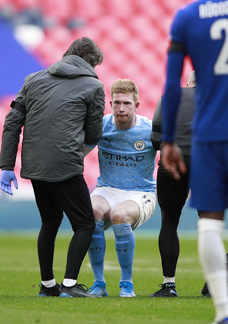 Manchester City's Kevin De Bruyne stands up helped by medical staff after injuring during the English FA Cup semifinal soccer match between Chelsea and Manchester City at Wembley Stadium in London, England, Saturday, April 17, 2021. (AP Photo/Ian Walton, Pool)
