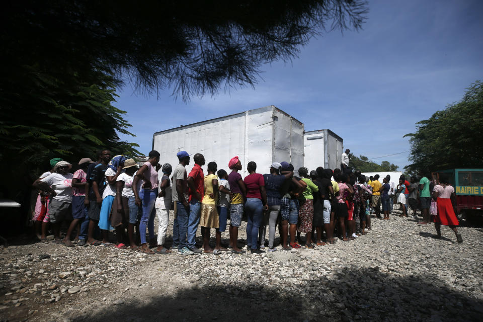 People wait near the front of a line hundreds of people long for government distributed food and school supplies to some residents of the Cite Soleil slum, in Port-au-Prince, Haiti, Thursday, Oct. 3, 2019. The administration of President Jovenel Moise tried to alleviate Haiti’s economic crunch on Thursday by distributing plates of rice and beans, sacks of rice, and school backpacks filled with four notebooks and two pens. (AP Photo/Rebecca Blackwell)