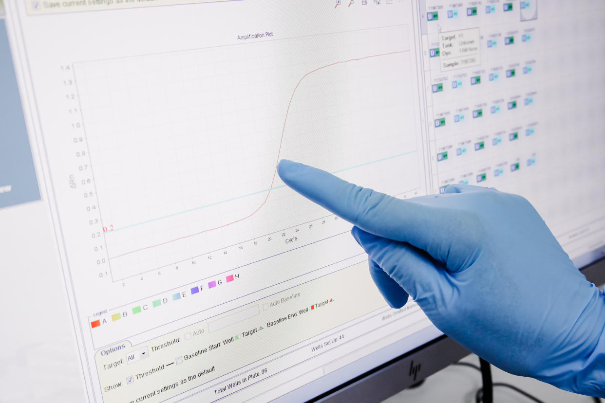 A gloved hand points to a graph on a computer screen.