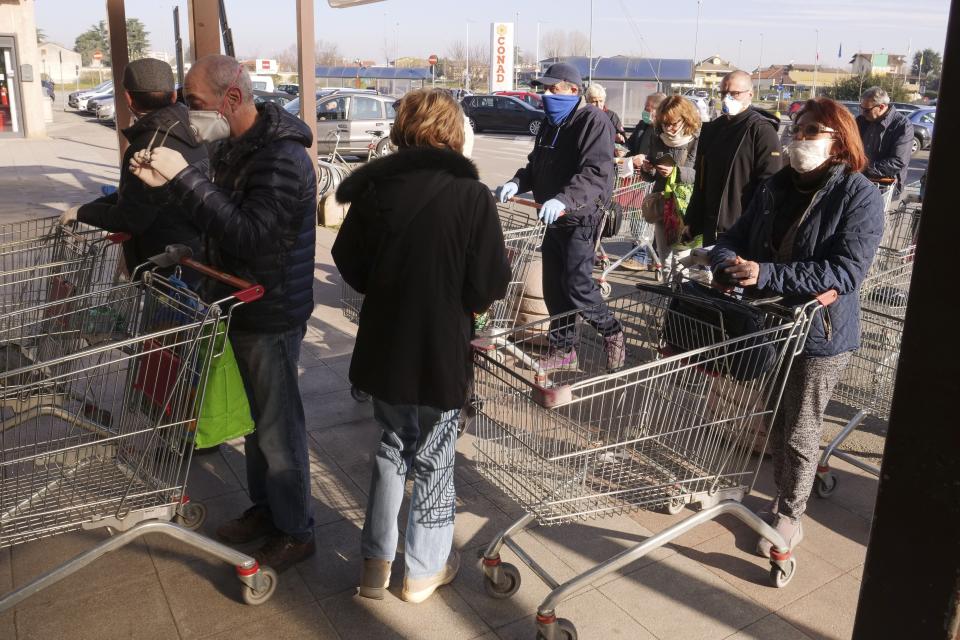 People queue outside a supermarket in Casalpusterlengo, Northern Italy, Monday, Feb. 24, 2020. Italy scrambled to check the spread of Europe's first major outbreak of the new viral disease amid rapidly rising numbers of infections and a third death. Road blocks were set up in at least some of 10 towns in Lombardy at the epicenter of the outbreak, including in Casalpusterlengo, to keep people from leaving or arriving. (AP Photo/Paolo Santalucia)