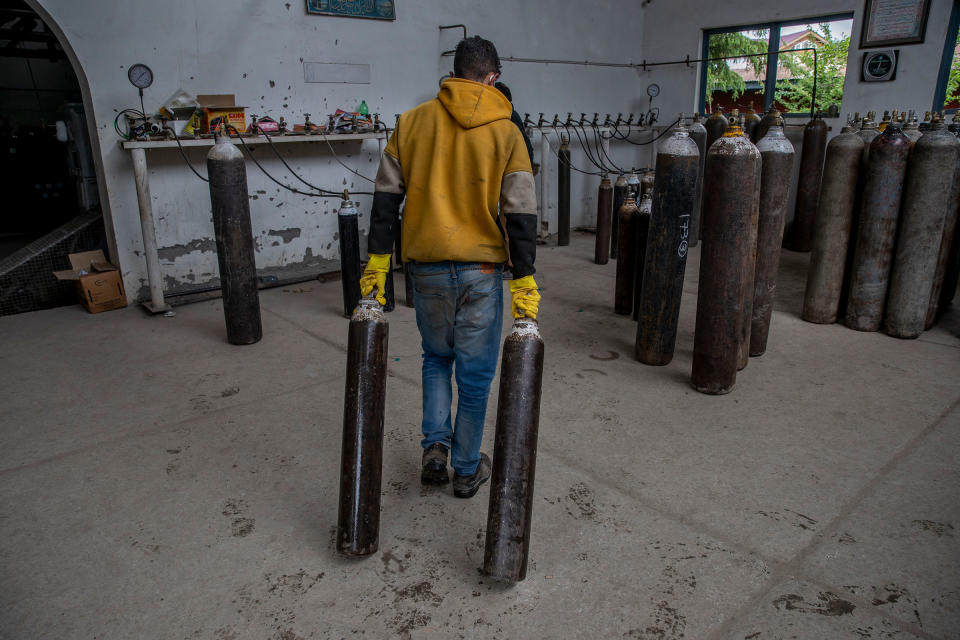 A worker moves empty oxygen cylinders for refilling at a gas supplier facility in Srinagar on May 11, 2021.<span class="copyright">Dar Yasin—AP</span>