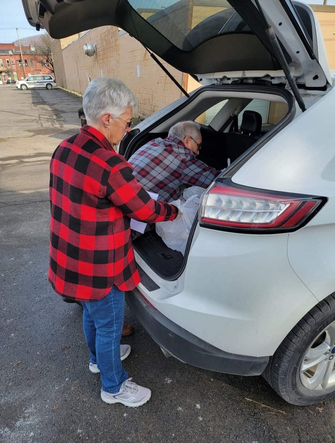 Act-N-Do volunteers place free Thanksgiving Day dinners to a vehicle at Christ Episcopal Church, on East First Street in Corning