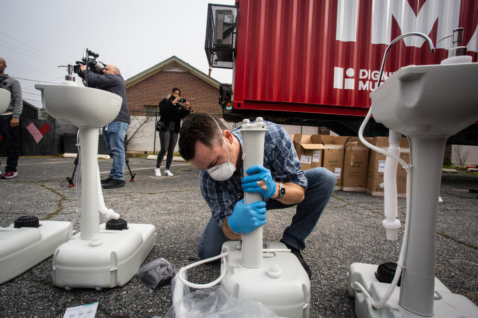 A volunteer worker assembles a portable wash station on Thursday, March 19, 2020 in College Park, Georgia. The wash stations were distributed by hip hop recording artist Lecrae and volunteers with Love Beyond Walls, a non-profit, throughout Atlanta in areas with a high density of homeless persons. (AP Photo/ Ron Harris)