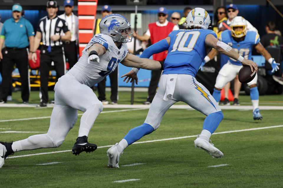 Justin Herbert of the Los Angeles Chargers runs with the ball against Aidan Hutchinson of the Detroit Lions during the first half at SoFi Stadium on November 12, 2023 in Inglewood, California.