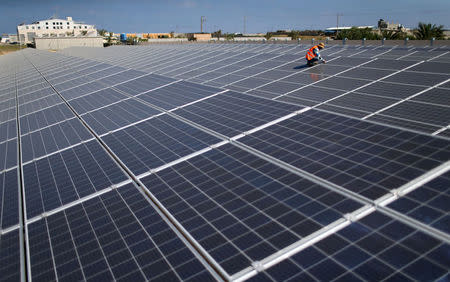 A Palestinian worker installs solar panels at Khan Younis Waste Water Treatment Plant, in the southern Gaza Strip July 31, 2018. REUTERS/Ibraheem Abu Mustafa