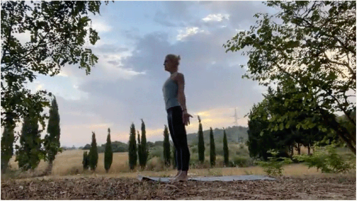 Woman standing on her yoga mat outside at sunrise