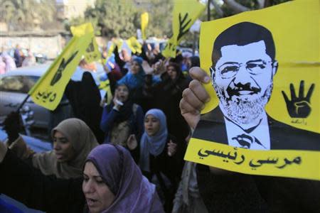 Supporters of the Muslim Brotherhood and ousted Egyptian President Mohamed Mursi shout slogans against the military and interior ministry while holding his poster and gesturing with four fingers in front of Al Rayyan mosque after Friday prayers in the southern suburb of Maadi, on the outskirts of Cairo December 27, 2013. REUTERS/Amr Abdallah Dalsh