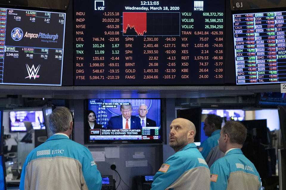 FILE - In this March 18, 2020, file photo, traders at the New York Stock Exchange watch President Donald Trump's televised White House news conference. (AP Photo/Mark Lennihan, File)