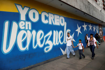 Venezuelan citizens walks past a mural depicting former Venezuela's late President Hugo Chavez and a graffiti that reads "i believe in Venezuela" in Caracas, Venezuela, December 1, 2016. REUTERS/Ueslei Marcelino