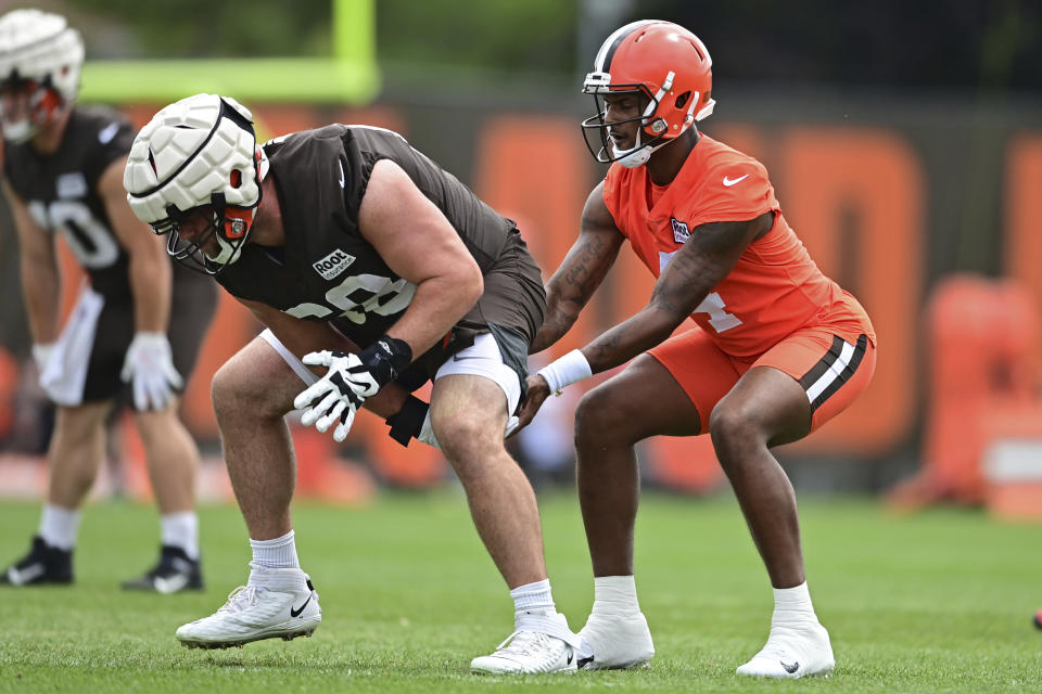 Cleveland Browns quarterback Deshaun Watson, right, takes a snap from guard Michael Dunn during an NFL football practice in Berea, Ohio, Tuesday, Aug. 16, 2022. (AP Photo/David Dermer)
