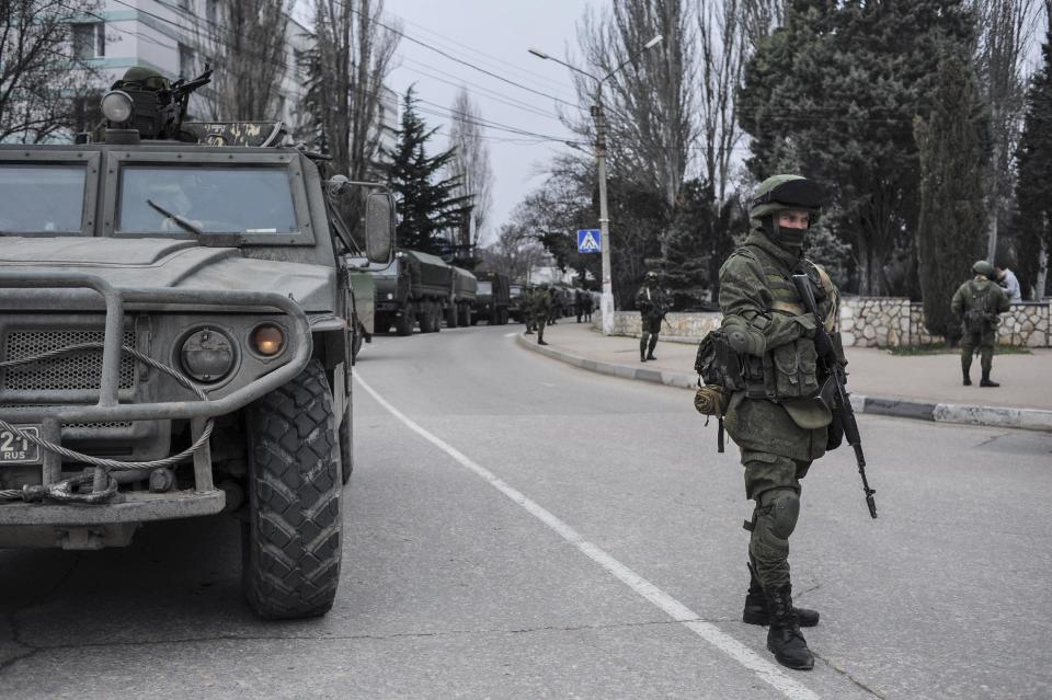 Troops in unmarked uniforms stand guard in Balaklava on the outskirts of Sevastopol, Ukraine, Saturday, March 1, 2014. An emblem on one of the vehicles and their number plates identify them as belonging to the Russian military. Ukrainian officials have accused Russia of sending new troops into Crimea, a strategic Russia-speaking region that hosts a major Russian navy base. The Kremlin hasn't responded to the accusations, but Russian lawmakers urged President Putin to act to protect Russians in Crimea. (AP Photo/Andrew Lubimov)