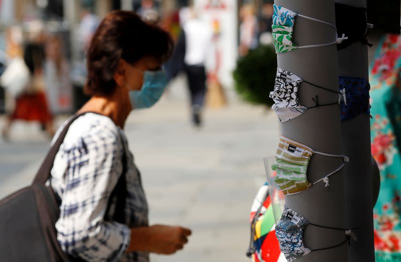 A woman stands next to protective masks on display in Vienna