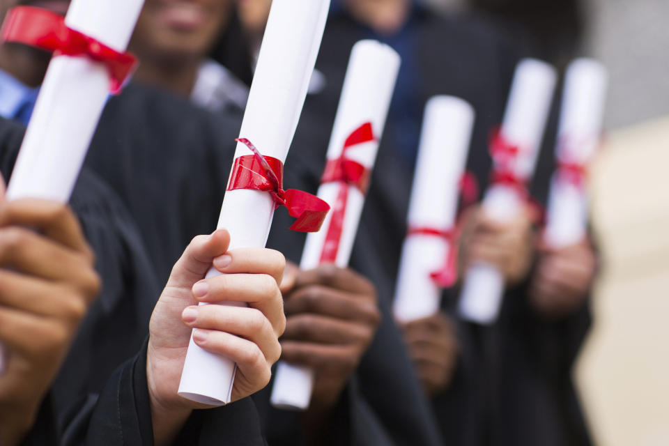 group of multiracial graduates holding diploma