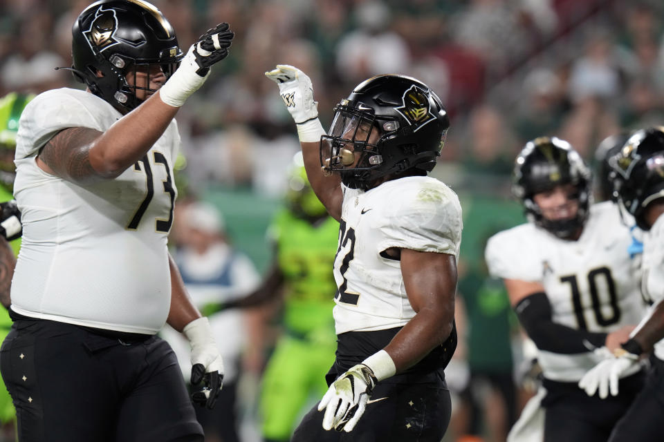 UCF running back RJ Harvey (22) celebrates with offensive lineman Samuel Jackson (73) after scoring on a 3-yard touchdown run against South Florida during the first half of an NCAA college football game Saturday, Nov. 26, 2022, in Tampa, Fla. (AP Photo/Chris O'Meara)