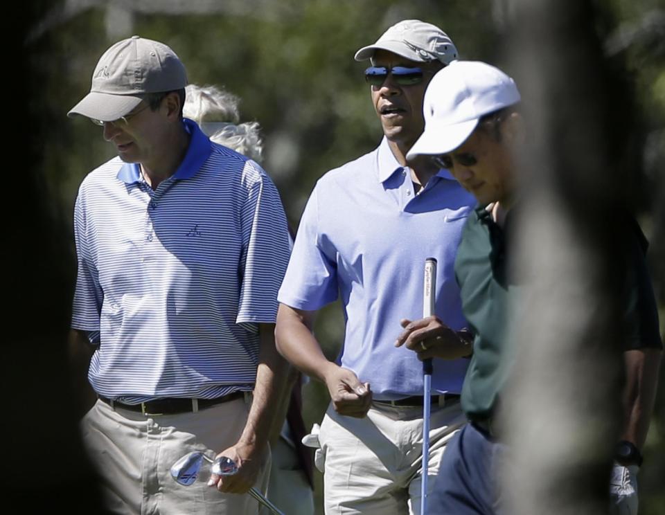 President Barack Obama, center, walks with Comcast CEO Brian Roberts, left, and World Bank President Jim Kim, right, while golfing at Vineyard Golf Club in Edgartown, Mass., on the island of Martha's Vineyard Wednesday, Aug. 14, 2013. President Obama and his wife Michelle are vacationing on the island. (AP Photo/Steven Senne)