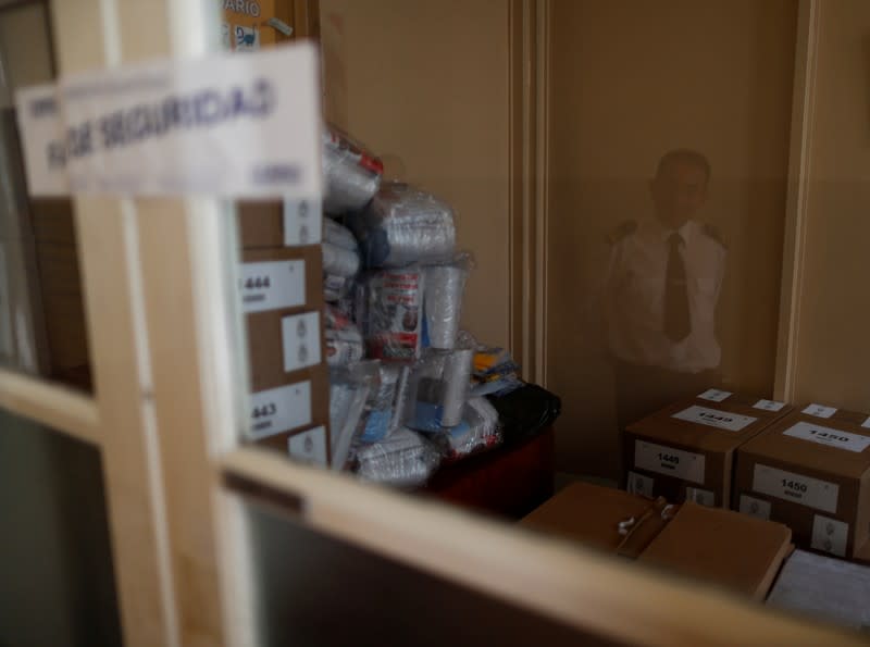 A security officer is reflected in a window as ballot boxes are stored in a school, which will serve as a polling station one day ahead of presidential elections in Buenos Aires