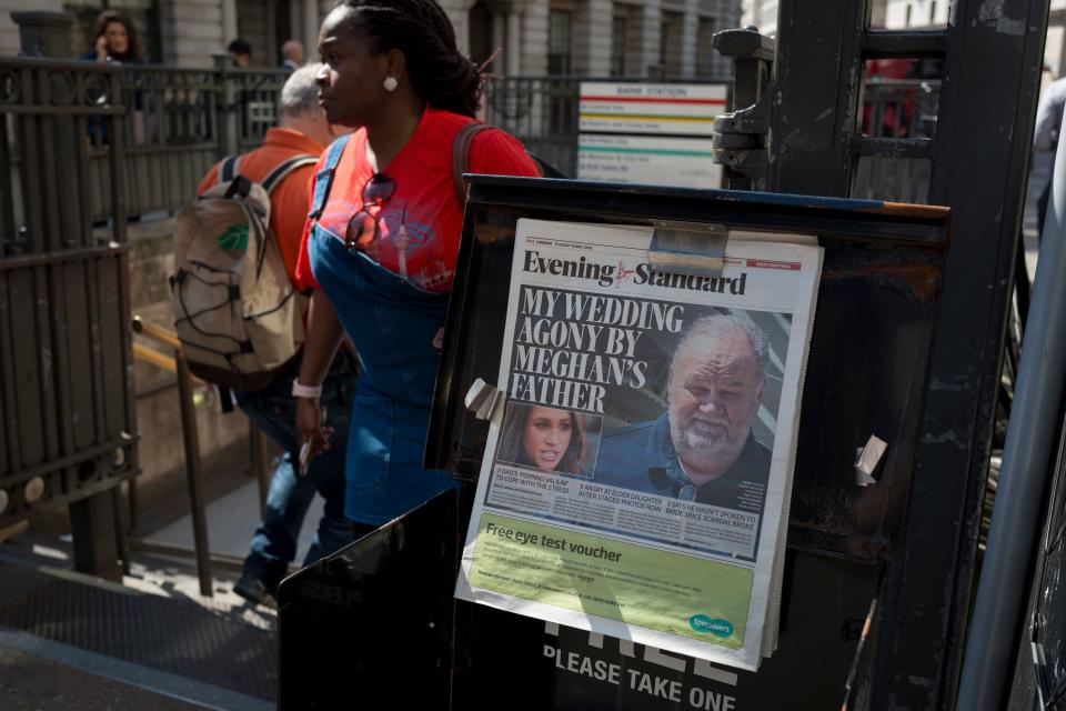 A newspaper dispenser with Meghan and her father on the front page