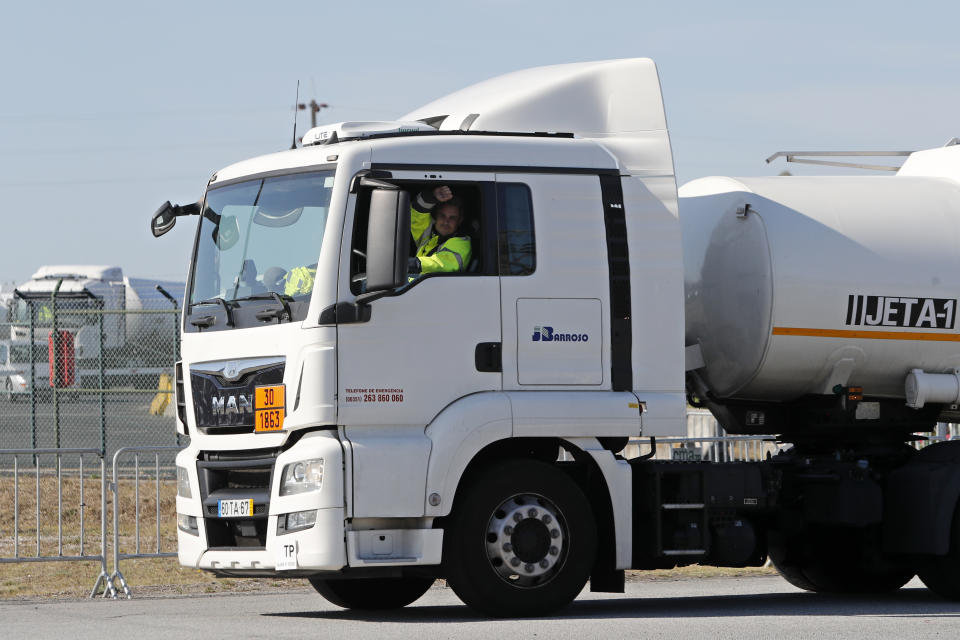 The driver of a jet fuel truck gestures to cheering truck drivers standing outside a fuel depot in Aveiras, outside Lisbon, Monday, Aug. 12, 2019. Portugal is rationing gas as a precaution after some 2,000 tanker truck drivers began an open-ended strike over pay on Monday. The government has set a limit of 25 liters (6.6 gallons) for customers at gas stations until further notice. (AP Photo/Armando Franca)