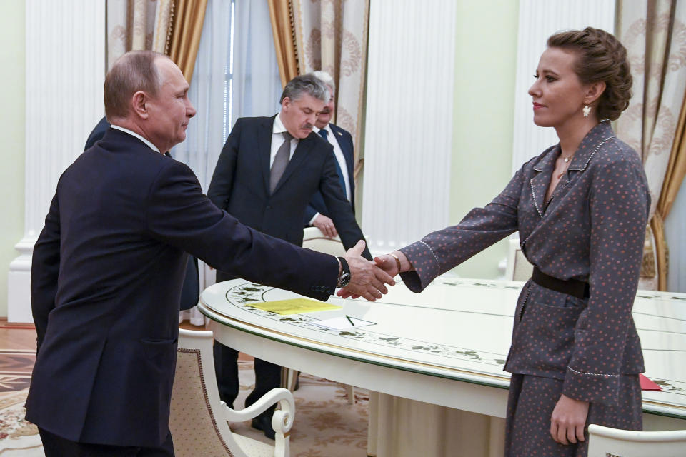 FILE - Russian President Vladimir Putin, left, greets Ksenia Sobchak, right, during his meeting with opposition candidates who ran against him in presidential election, at the Kremlin in Moscow, Russia, Monday, March 19, 2018. Russian investigators on Wednesday raided the home of Ksenia Sobchak, the glamourous daughter of Russian President Vladimir Putin's one-time boss, in a move that has sent shockwaves through the country's political scene. (Yuri Kadobnov/Pool Photo via AP, File)