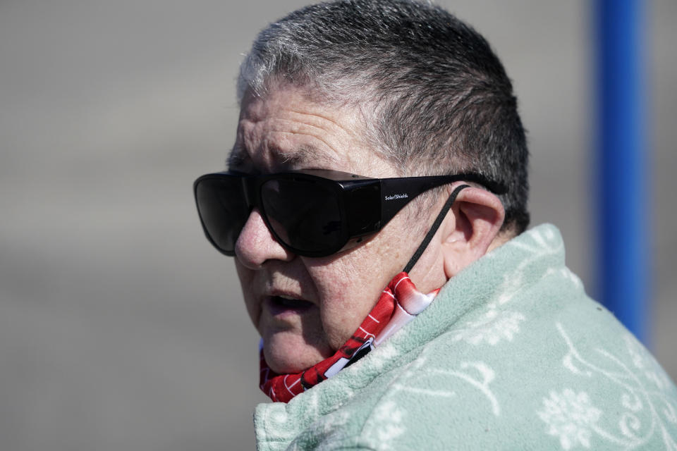 Pat Brown waits at a bus stop in Kansas City, Mo., Wednesday, March 3, 2021. Brown knows she needs the vaccine because her asthma and diabetes put her at higher risk of serious COVID-19 complications. But Brown hasn’t attempted to schedule an appointment and didn’t even know if they were being offered in her area yet; she says she is too overwhelmed. (AP Photo/Orlin Wagner)