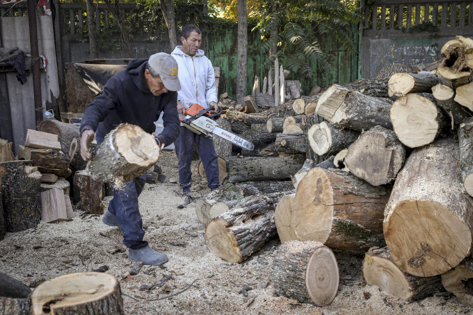 Men cut wood for heating outside Chisinau, Moldova, Saturday, Oct. 15, 2022. Europe's energy crisis, triggered by Russia slashing natural gas flows amid its war against Ukraine, has forced some people to turn to cheaper heating sources like firewood as the weather gets colder. But as more people stock up and burn wood, prices have skyrocketed, shortages and thefts have been reported, and scams are emerging. (AP Photo/Aurel Obreja)