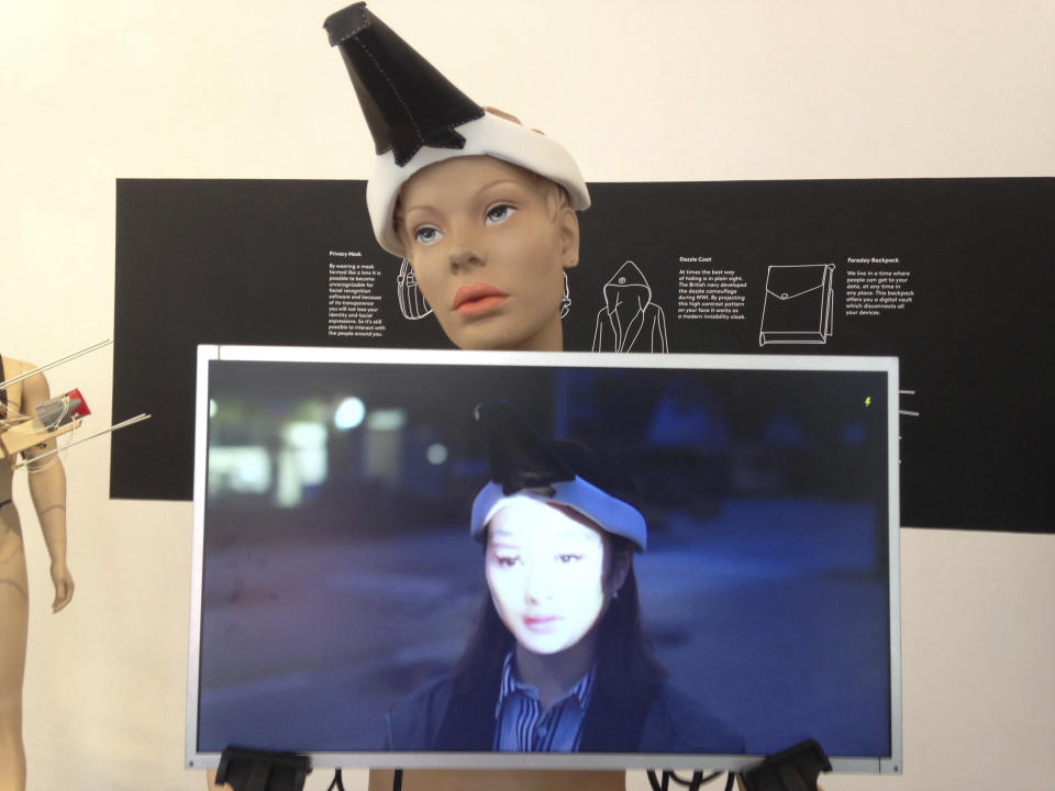 This 2017 photo provided by artist Jing-cai Liu shows her work titled "Wearable Face Projector" at a gallery in Utrecht, Netherlands. A 2017 video by Liu showing her demonstrating the conceptual art piece, on screen at center, began circulating widely on social media in early October 2019 after Hong Kong instituted an emergency ordinance to ban masks at rallies. Liu said her piece was not intended to be political. She found out that people were sharing her video in relation to the protests when her friends began tagging her in posts with the false caption claiming that protesters in Hong Kong use wearable face projectors to disable the facial recognition system used by the government. (Jing-cai Liu via AP)