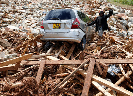 A man gestures next to his car after it was swept into debris left by Cyclone Idai in Chimanimani, Zimbabwe, March 23, 2019. REUTERS/Philimon Bulawayo/Files