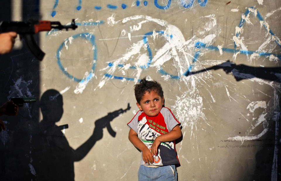 <p>A Palestinian boy reacts as youths frighten him by pointing their toy guns at him, in an alley in the West Bank refugee camp of Al-Amari in Ramallah, June. 16, 2009. (Photo: Muhammed Muheisen/AP) </p>